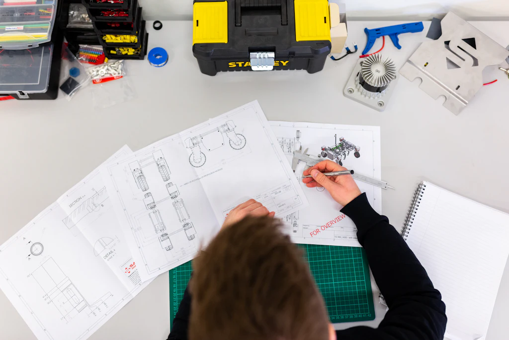 Tecnico che misura un disegno tecnico con un calibro